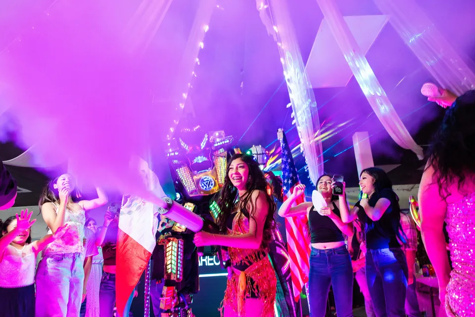 Guests celebrating under colorful quinceañera reception lights