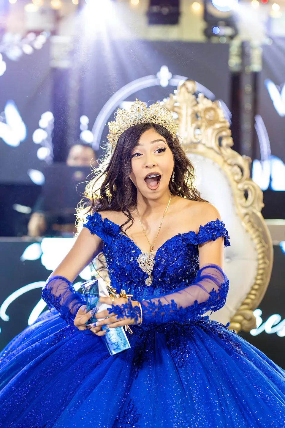 A quinceañera in a blue gown and crown enjoying her celebration
