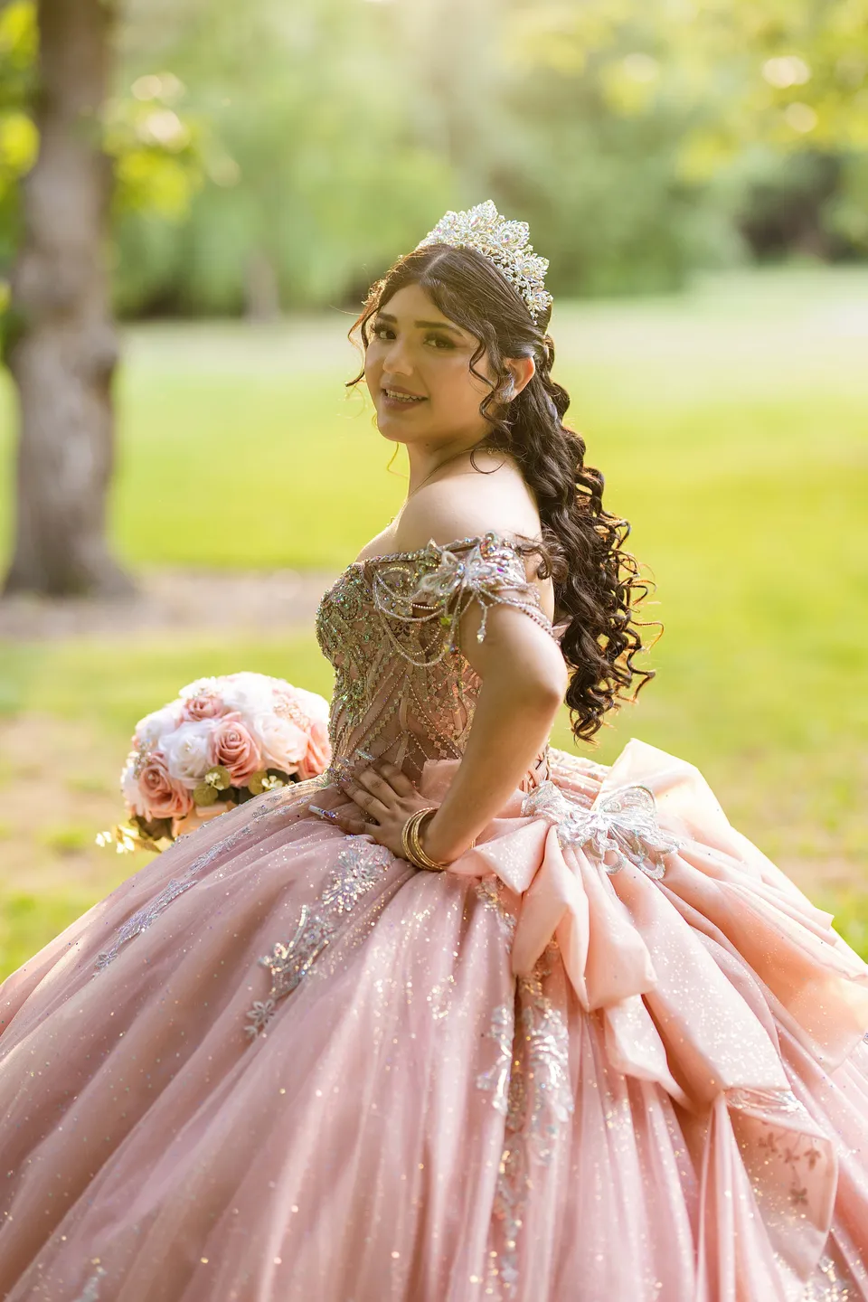 A close portrait of a quinceañera in a pink gown with bouquet