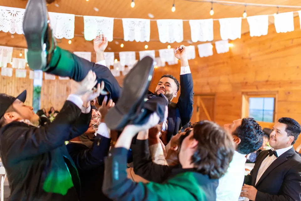 Wedding guests lifting the groom during the reception