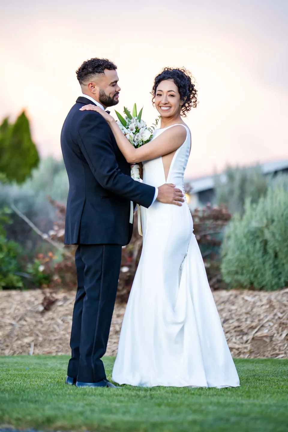 The bride and groom embracing outdoors at dusk
