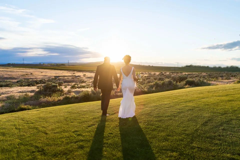 A newly married couple walking across the lawn at sunset